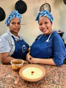 Two female chefs serving a bowl of soup and smiling