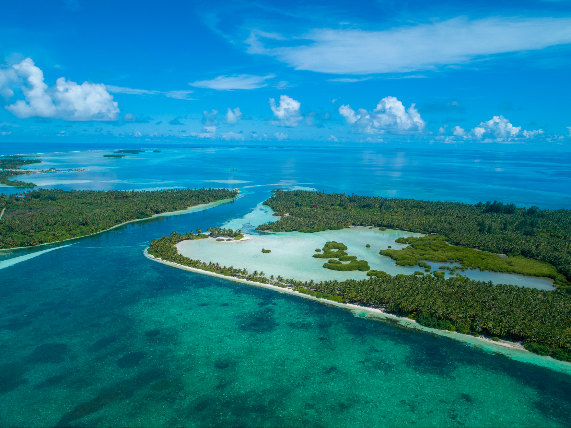 ocean blue channel between two islands flows into shallow mangrove area