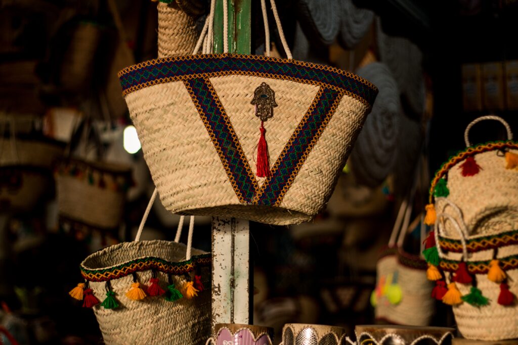 Vibrant woven baskets from Gabes, Tunisia showcasing colorful decorations, traditional patterns, and a Hand of Fatima (Hamza) pendant.